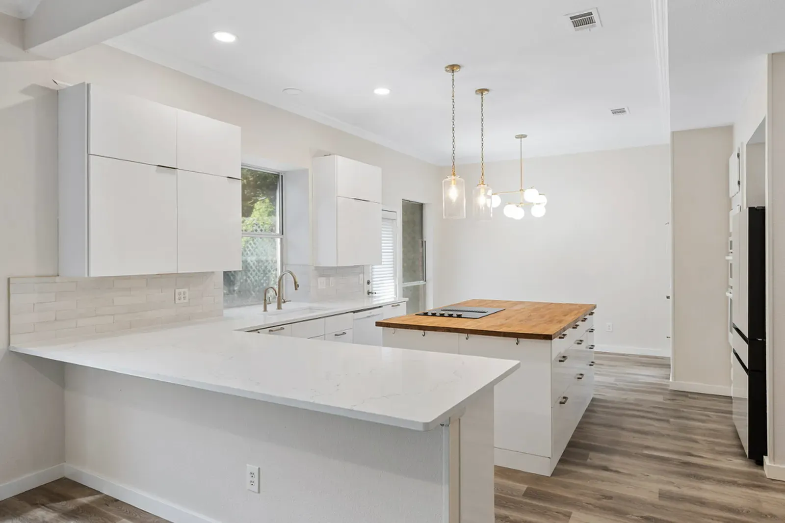 New white quartz countertops with a wood-top island and pendant lights in Addison, TX