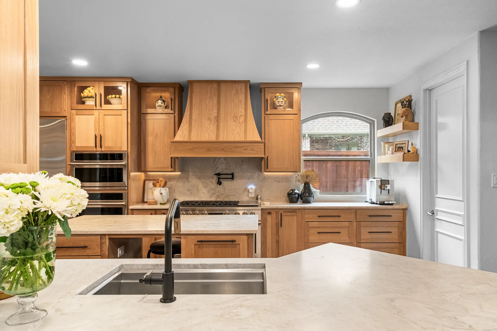 Taj Mahal quartzite kitchen island with a black faucet and white oak cabinetry, fabricated and installed by Dallas Countertop in Plano, TX