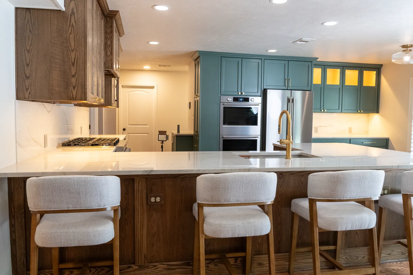 Quartzite island with bar seating and green pantry cabinets in Preston Hollow, Dallas